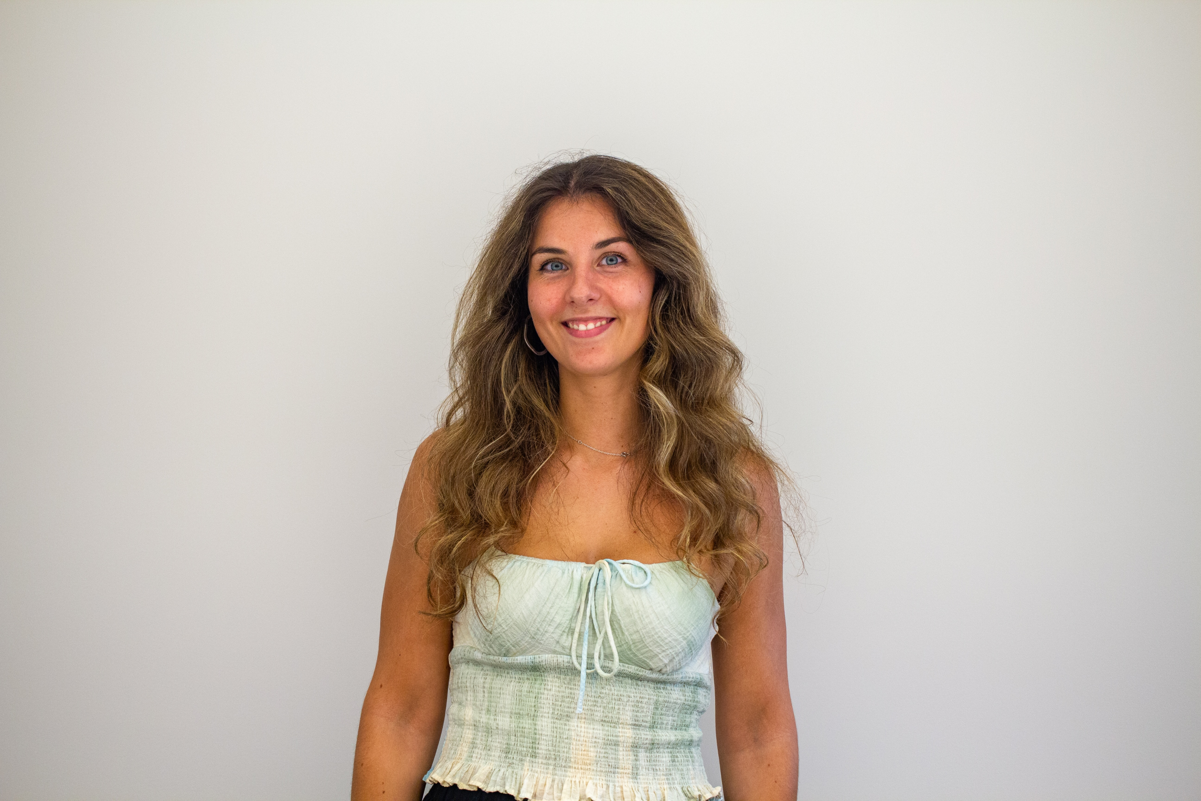 Portrait of a woman with brown hair on a flat gray background.